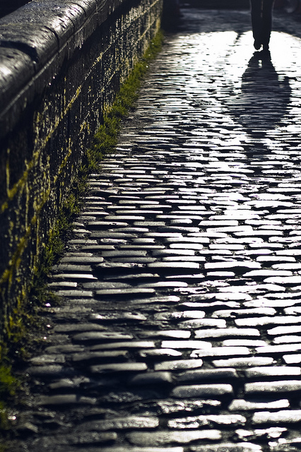 Figure walking down a cobblestone street