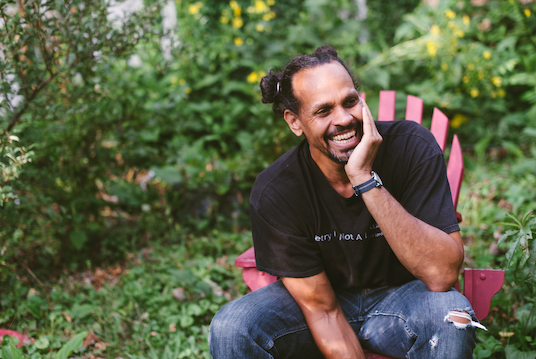 headshot of ross gay sitting in a garden