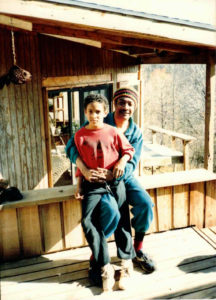 Image of a boy and a man seated in front of a house