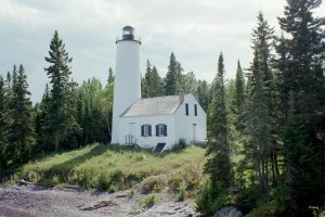 Image of a lighthouse surrounded by conifer trees.