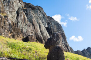 Image of a field leading up to a cliff with a moai statue.