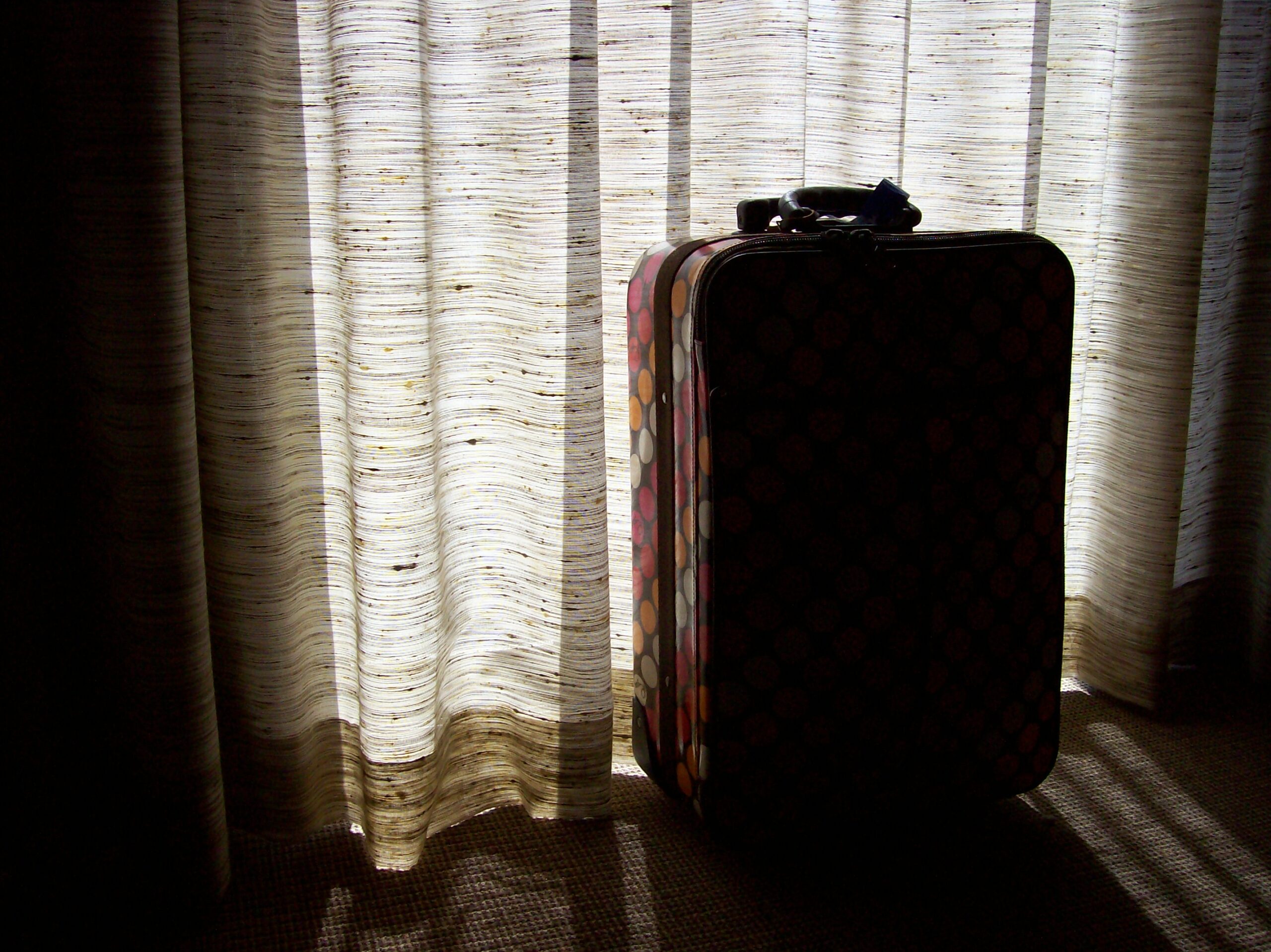 Suitcase in front of a curtained window