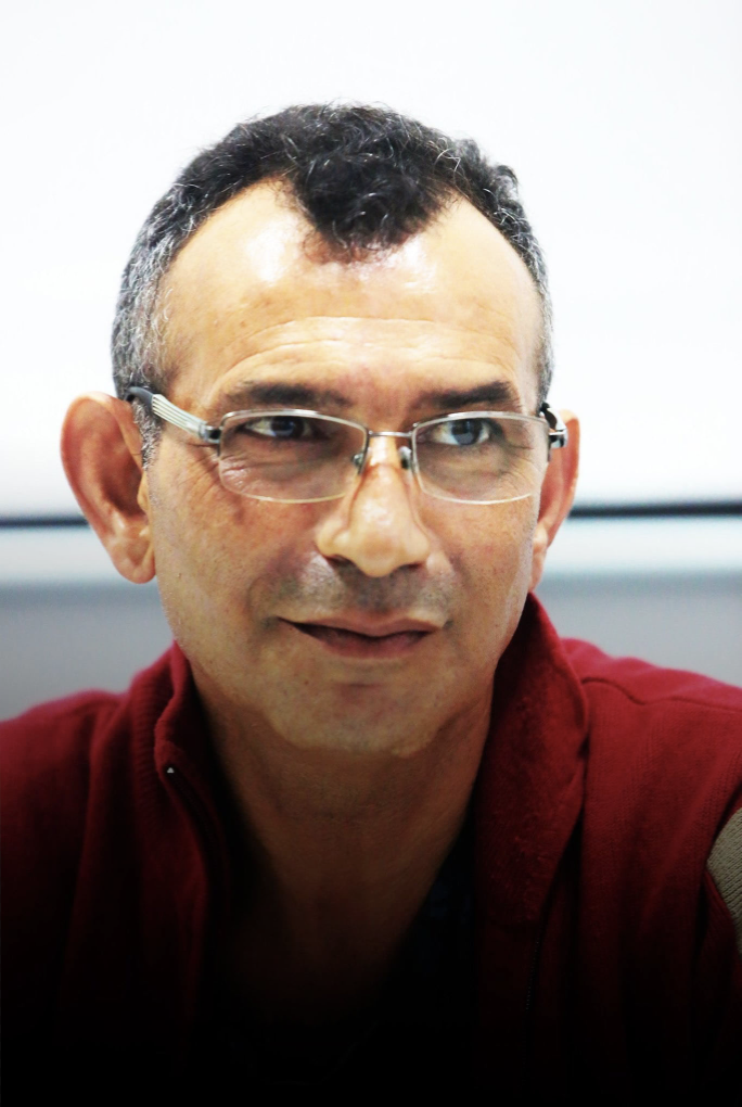 Headshot of Abdelmajid Haouasse, a middle aged North African man wearing glasses and a red polo shirt