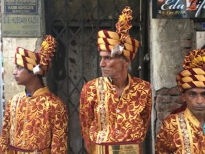 Image of three members of a marching band, dressed in orange and yellow.