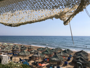 Image of a beach with chairs and umbrellas made out of twine.