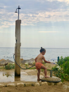 Image of a little child at the beach playing with the hose of an umbrella.