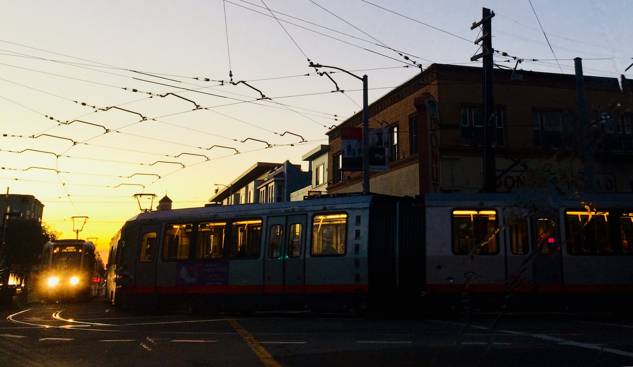 An image of the N Judah trains rounding the corner of 9th and Judah at twilight.