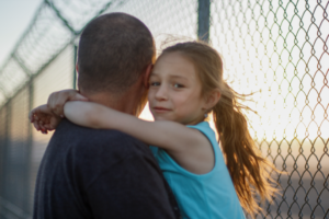 man holding a girl, up close. The girl is facing us.