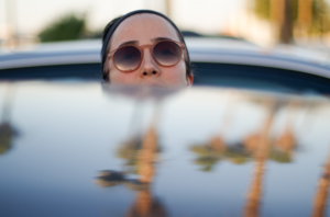 Woman sticking her head out from behind a car.