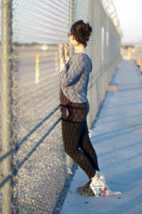 A woman is leaning against a fence.