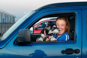 Woman holding a dog in a blue car.