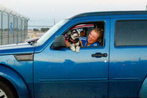 Woman holding a dog in a blue car.