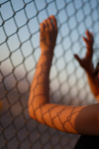 Hand holding onto a chainlink fence.