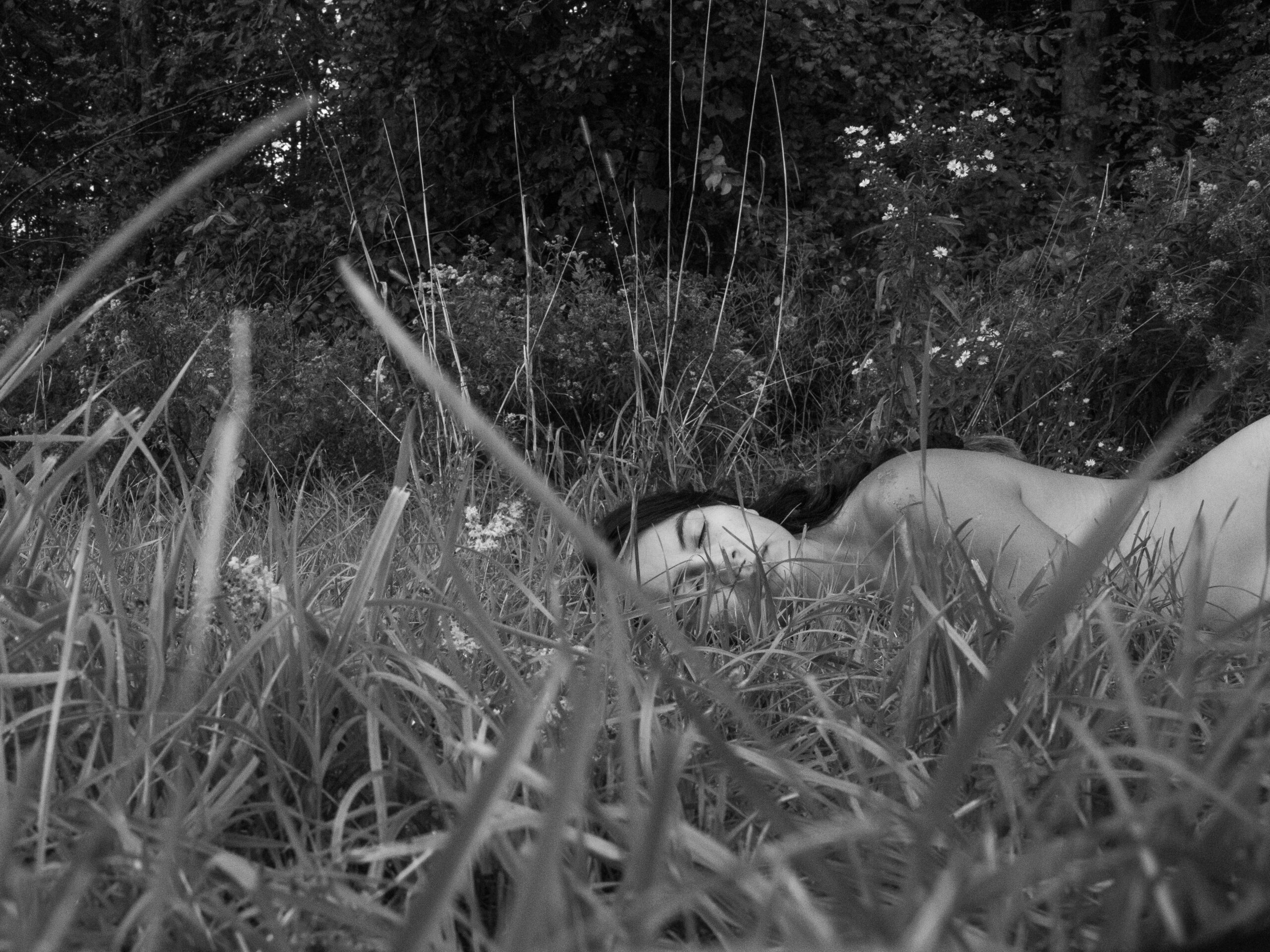 Black and white photo of a woman lying down in the grass.