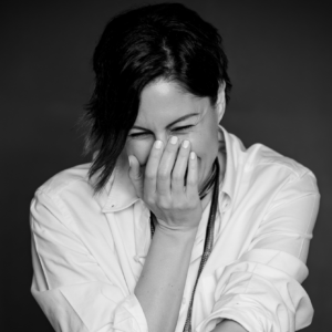 Zeina Hashem Beck's headshot: a black and white photo of a woman laughing.