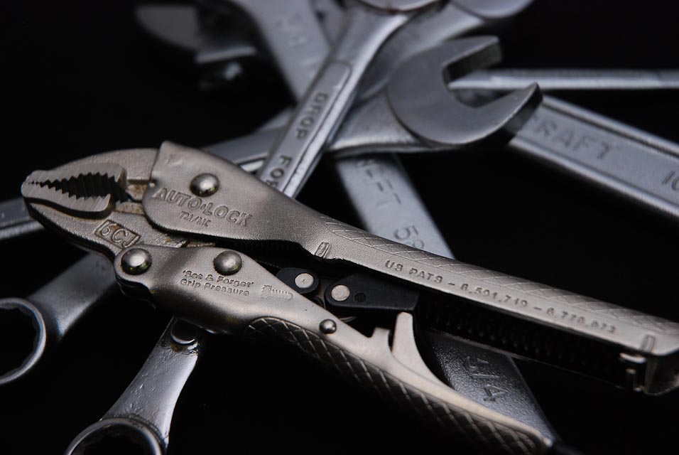 Image of wrenches stacked messily against black background