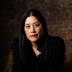 Victoria Chang's headshot: an asian woman wearing black against a dark brown background.