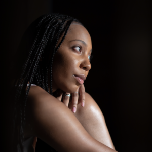 Jordan Honeyblue's headshot: Black woman against a black background facing to the side.