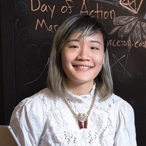 Jennifer Shyue's headshot: Asian woman in a white shirt with a blackboard in the background. 