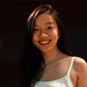 Stella Wong's headshot: Asian woman wearing a white tank top against a black background.