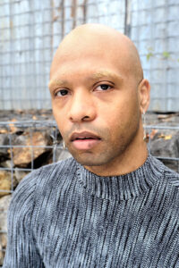 Nicholas Goodly's headshot: black person wearing a gray sweater.