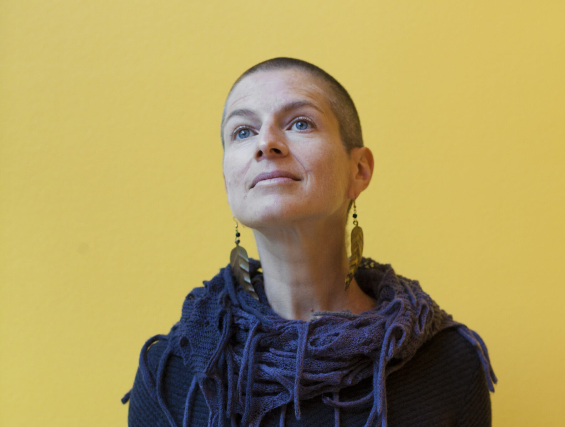 Portrait of Anna Badkhen in front of a yellow background. Photo Credit: Kael Alford/Panos Pictures.