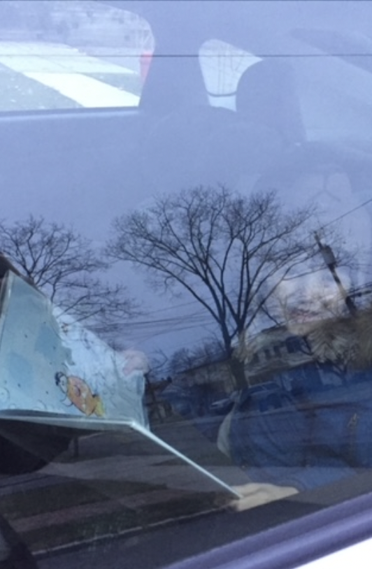 child in carseat with book through a car window