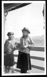 Black and white photo of two girls standing at a rail in front of a river.