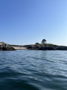 South Bristol, Maine. Small waves appear in a body of water. Land can be seen in the distance. Blue skies above. 