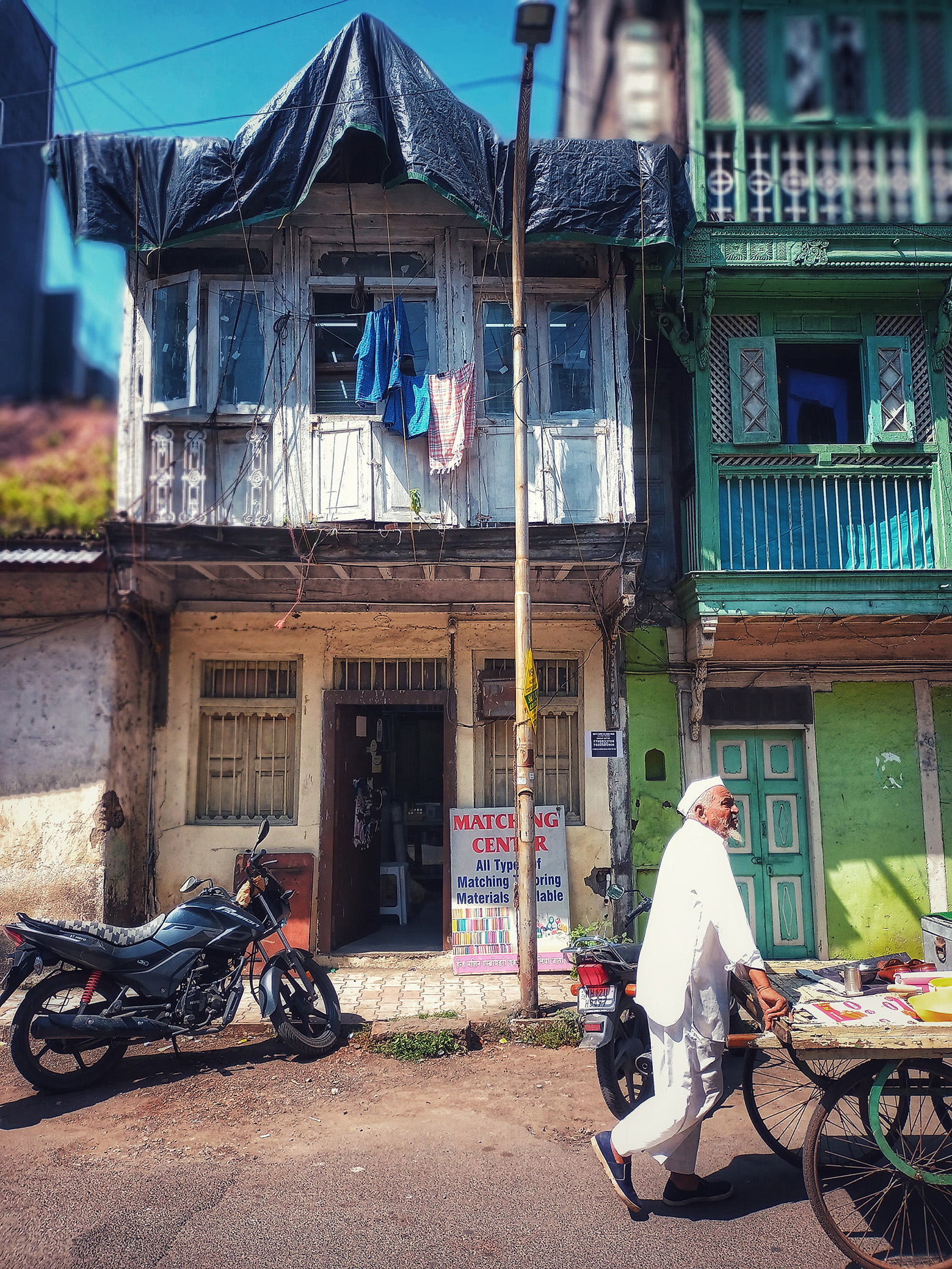 Man pushing a cart in front of a two-story white building