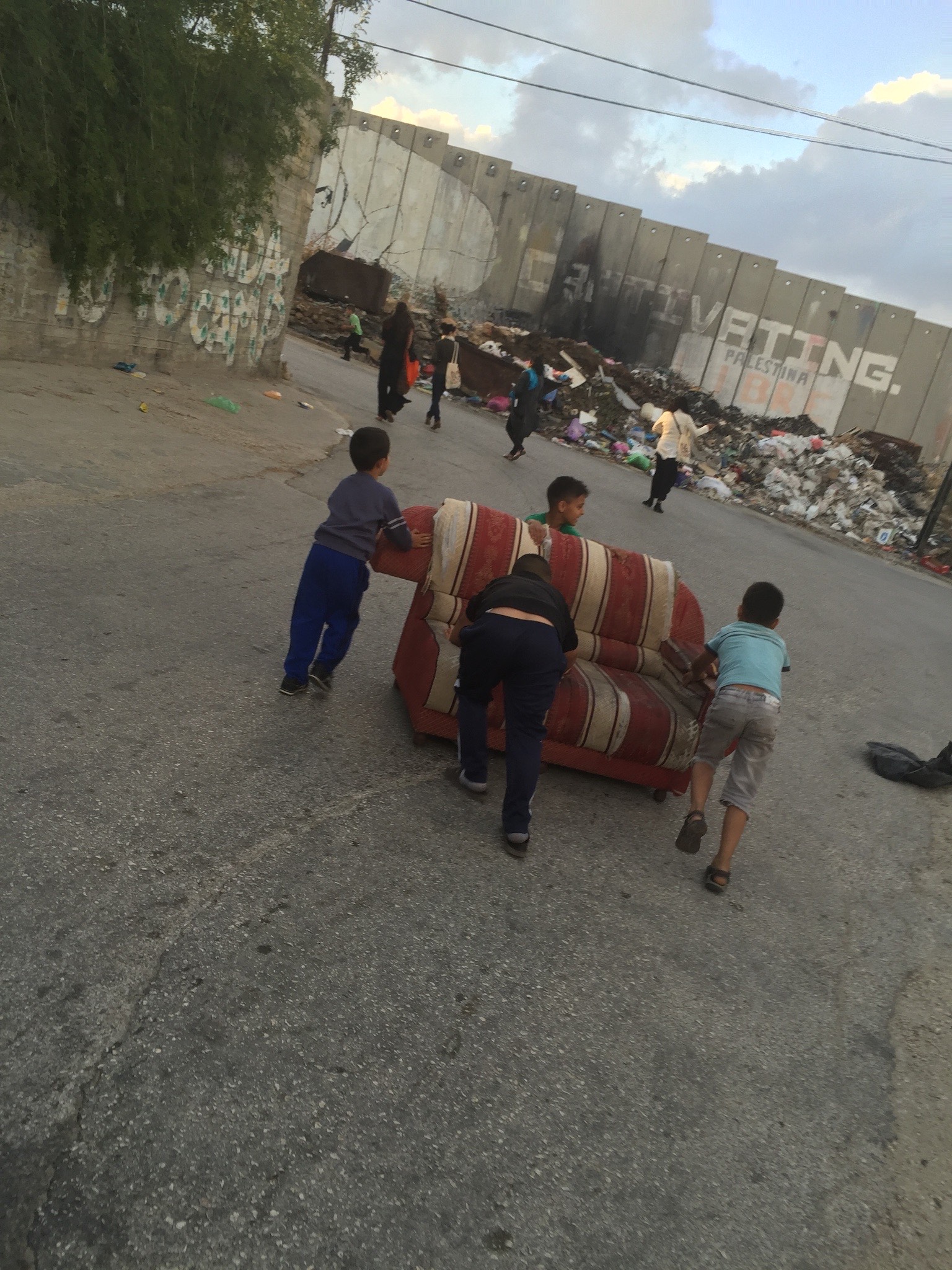 Young boys pushing a couch on a street in Palestine