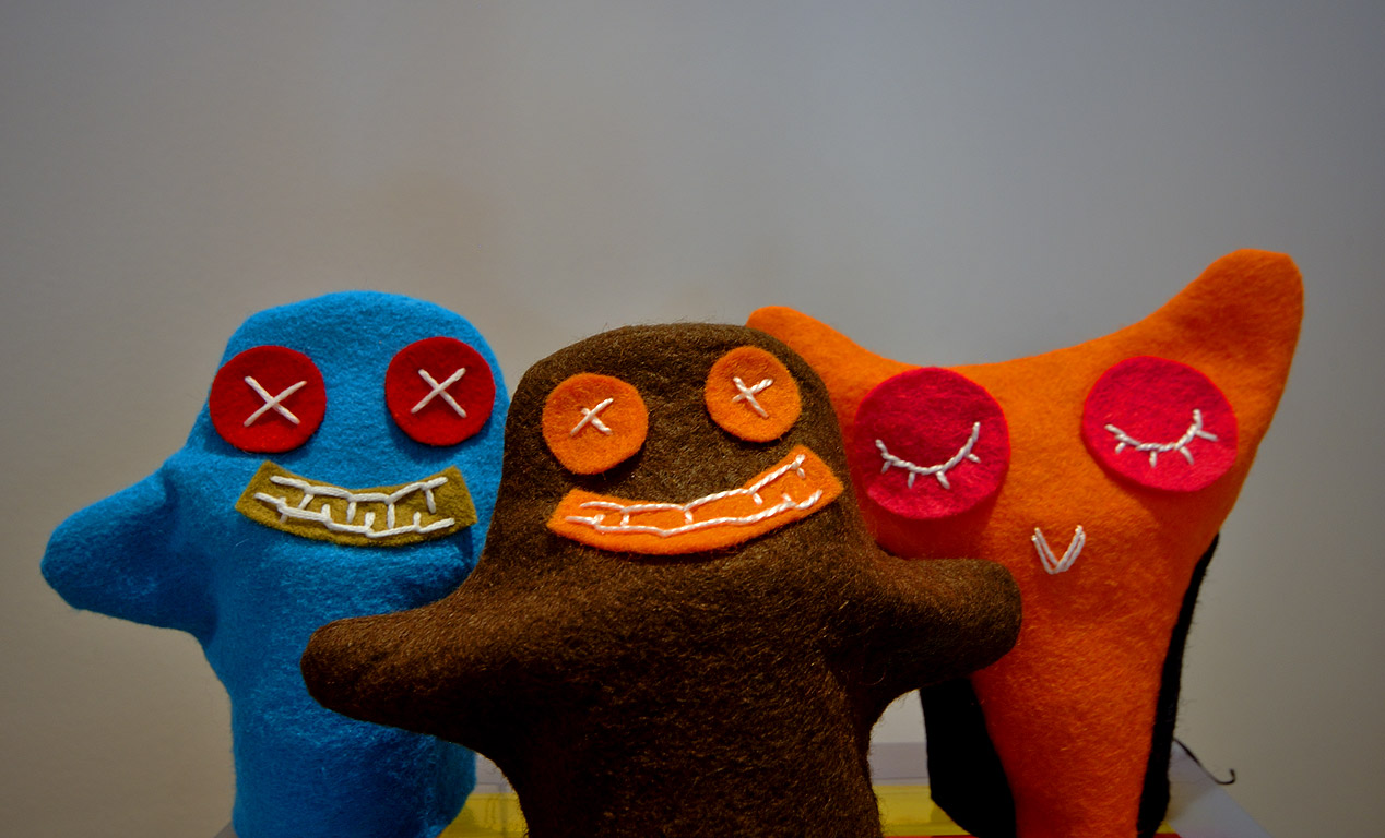 three hand puppets in shades of blue, brown, and orange
