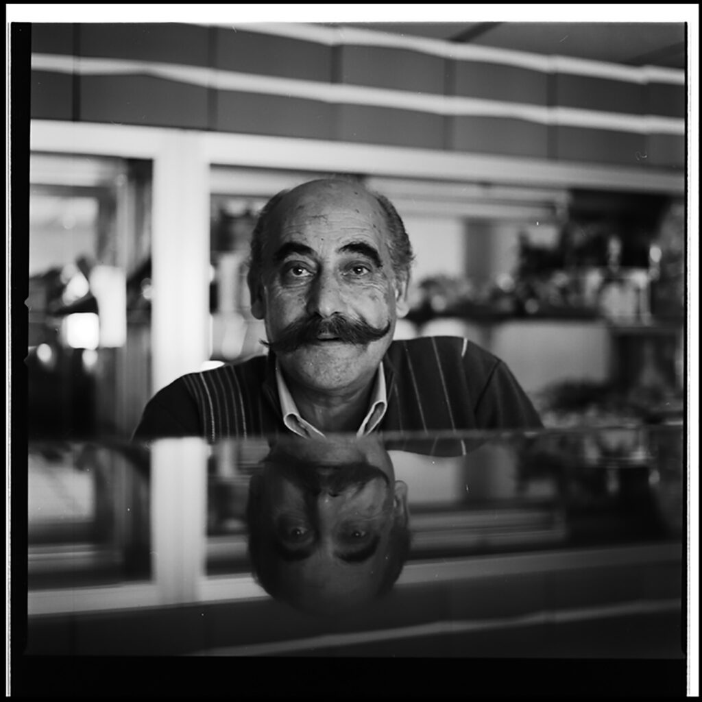 Man with large moustache reflecting over a metal countertop