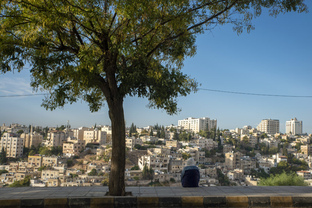 Woman sits by the roadside in Jabal Al-Lweibdeh, a popular spot known for its scenic view of downtown Amman. 