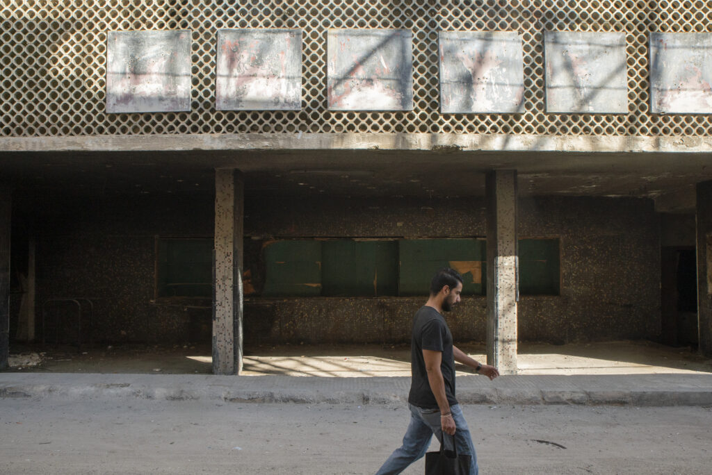 Lone pedestrian walks past the abandoned Al-Khayam Cinema. 