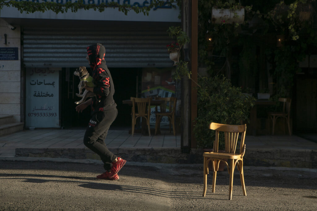 Man walks past a café’s outdoor seating in Jabal Al-Lweibdeh.