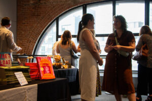 Guests mingle. A table on the left has copies of the panelists' books.
