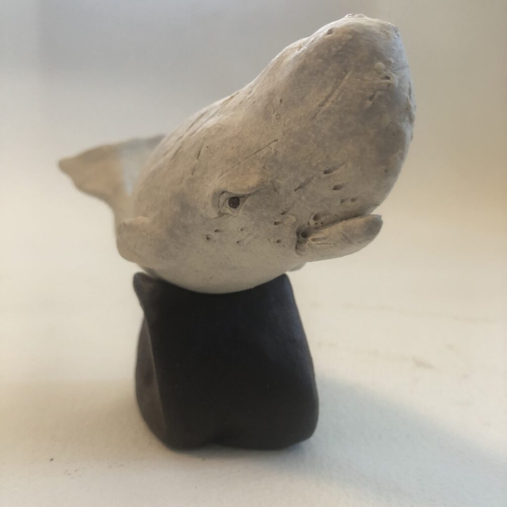 whale sculpture head on black stand against white background