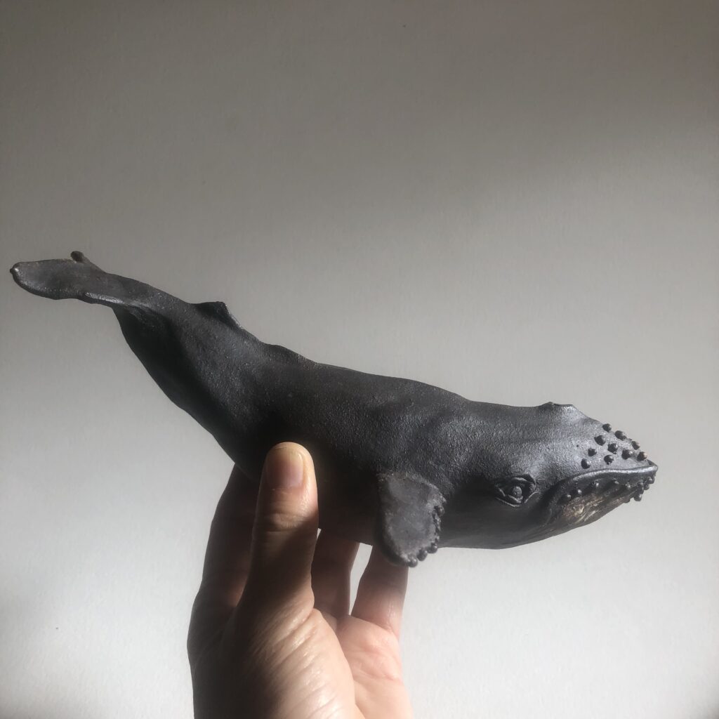 whale sculpture held against white background