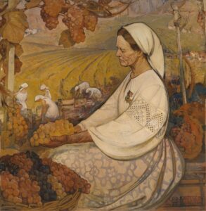 Woman kneels in a field holding grapes.