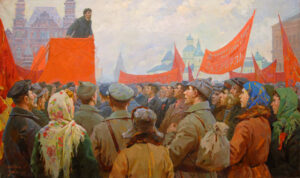 People listen to a speech.  Red banners above.