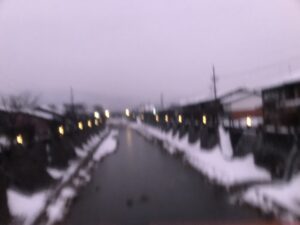 Blurry photo of a road with houses and snow.