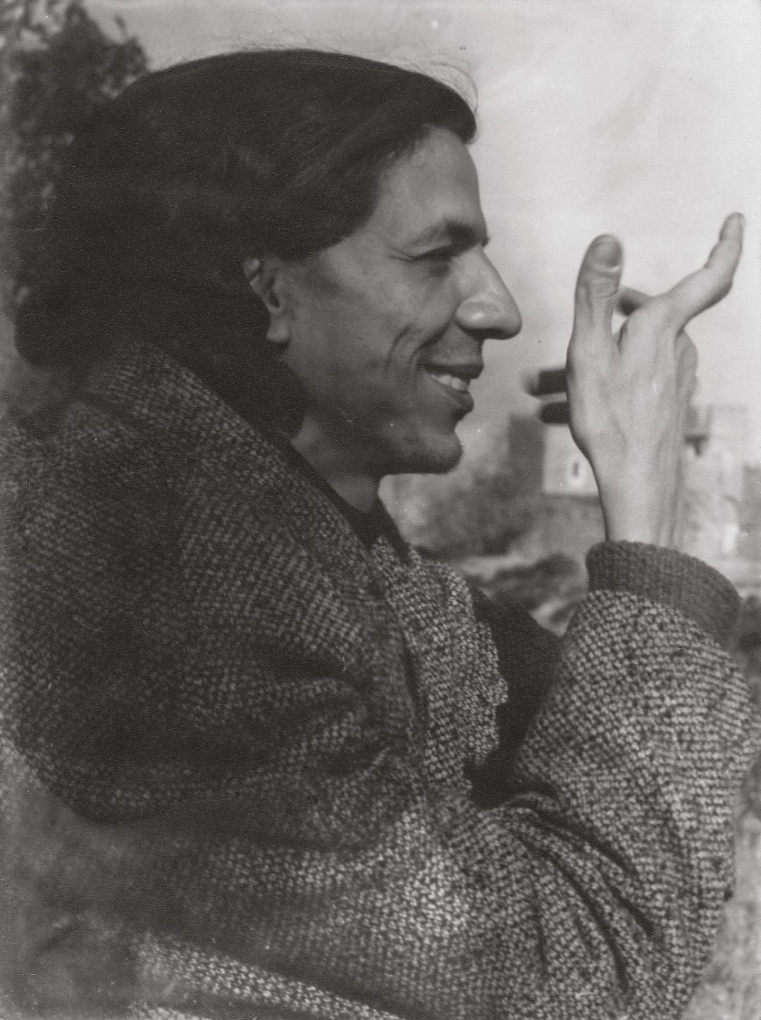 Portrait of person smiling and holding up their hand. Turned to the right.